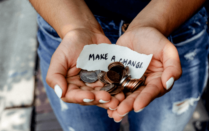 Cupped hands holding coins and a handwritten Make a Change note